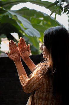 Side view of an Indian woman with henna tattoos on hands, enjoying nature in traditional attire.